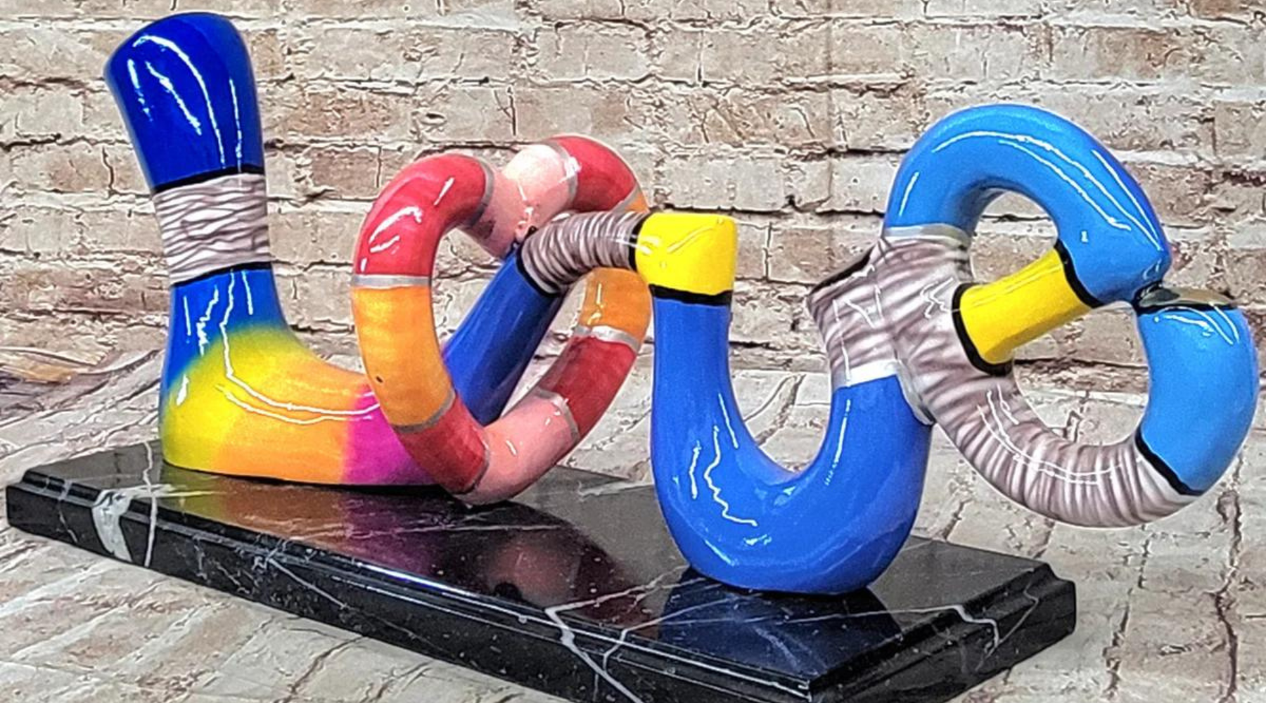 Colorful abstract resin or painted sculpture with looping shapes on a black marble base