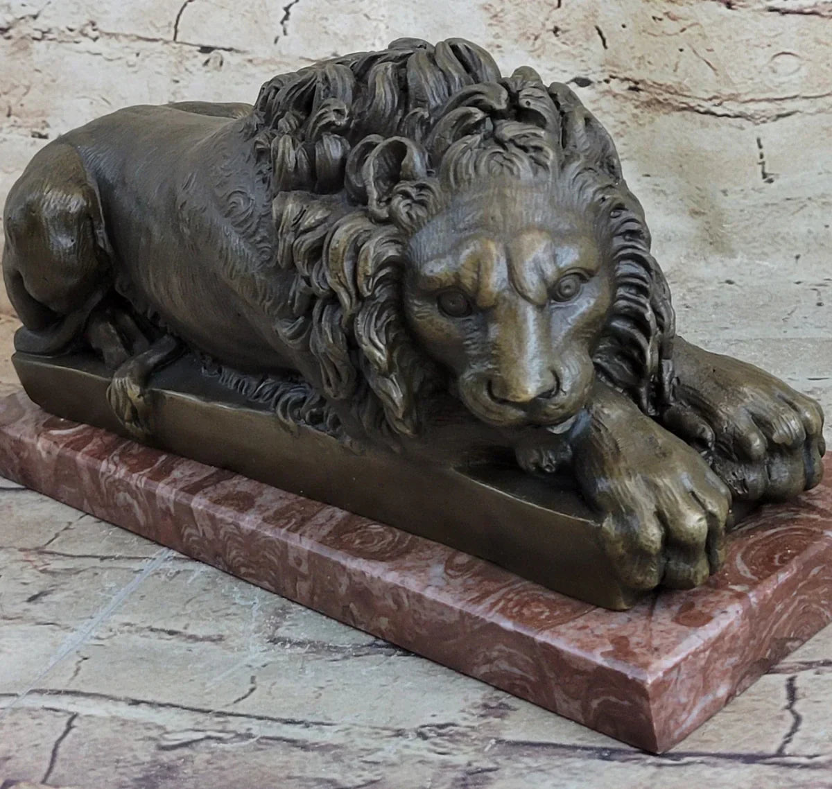 Bronze sculpture of a reclining lion with a detailed mane on a polished base