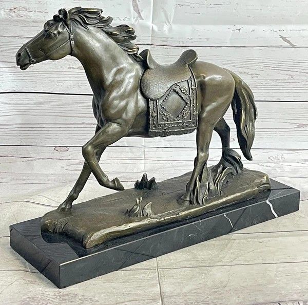 Bronze statue of a horse with a decorated saddle on a dark stone base