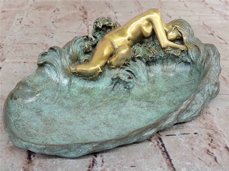 Close-up of Art Nouveau bronze sculpture: nude woman in gold patina reclining on turquoise wave base, evoking serene dynamism.
